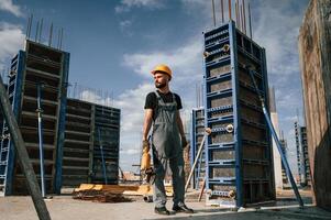 Standing ,with grinding machine in hands. Man,in uniform is working on the construction site photo