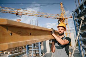 Against crane ,with wooden plank. ,Man in uniform is working on the construction site photo