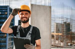 Posing for a camera, with notepad. Beautiful portrait. Man in uniform is working on the construction site photo