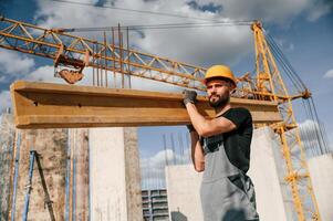 Front view ,of man that is in uniform holding wooden ,plank on the construction site photo