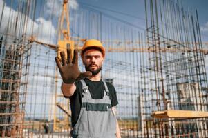 Closed area.. Stop gesture. Man in, uniform is working on the construction site photo