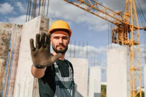 Stop gesture. Man in uniform is working on the construction site photo