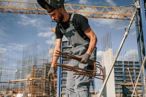 Working with rusty metal ,pieces. Man in uniform is on the construction site photo