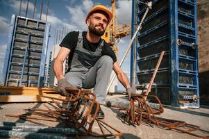 Metal ,pieces covered in rust. Man in ,uniform is working on the construction site photo