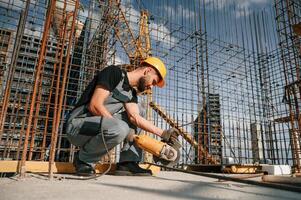 Using ,grinding machine to cut metal pieces. Man in uniform is working on the construction site photo
