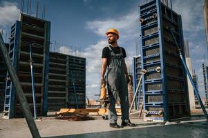 Standing with grinding machine in hands. Man in uniform is working on the construction site photo