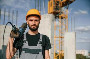 Portrait, of man that is in uniform, with the drill on the construction site photo