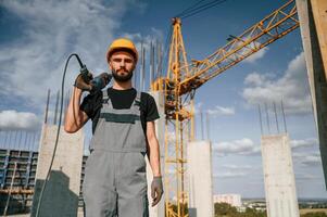 Portrait ,of man ,that is in uniform with the drill on the construction site photo
