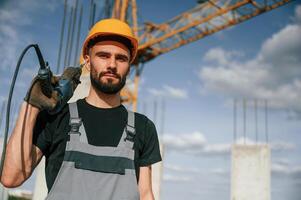 Portrait o,f man that is in uniform with, the drill on the construction site photo