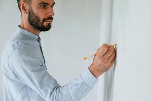 Doing marks by pencil on the wall. .The man is making repairs in the apartment photo