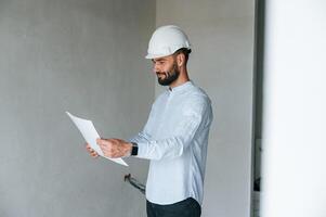 Holding ,and ,reading document. .The man is making repairs in the apartment photo