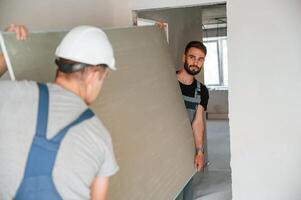 Moving construction, pieces by hands. Two men is making repairs in the apartment together photo