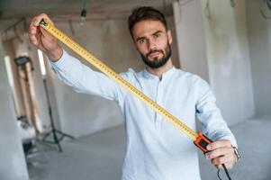 Holding, ruler measurement tool. The man is making repairs in the apartment photo