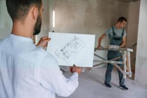 Working ,according to a plan. Two men is making repairs in the apartment together photo