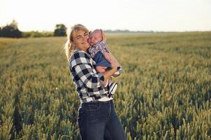 Standing ,and smiling, Happy, woman on the agricultural field is with little baby in the hands photo