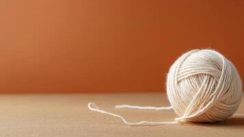 ball of wool yarn with delicate strand unwound on neutral background photo