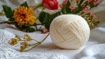 ball of white wool yarn with flowers on soft fabric background photo