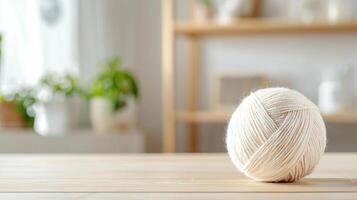 single white wool yarn ball sits on wooden table in cozy room photo