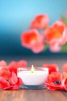 Candle and red flowers on wooden table with blurred background photo