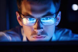 A man wearing glasses and looking at a computer screen photo