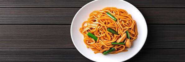 Savoring a colorful plate of chow mein with stir-fried noodles and vegetables in a cozy dining setting photo