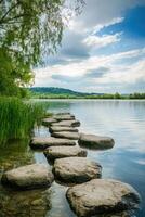 Serenity found in nature with stepping stones across a tranquil lake under a clear sky photo