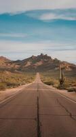 A road in the desert with a cactus in the foreground photo
