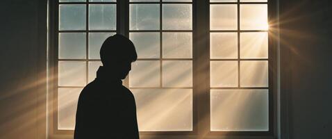 Silhouette of a man standing in front of a window photo