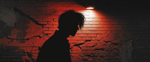 Silhouette of a man casting a shadow on a weathered brick wall in an urban setting with dramatic lighting photo