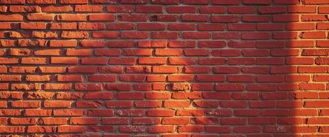 Red brick wall with warm sunlight casting shadows and highlights on the surface providing texture and depth with Copy Space photo