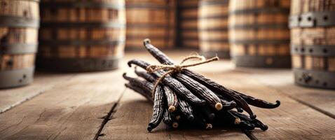 Bunch of Dark Brown Vanilla Beans Tied with Twine Surrounded by Rustic Stacked Wooden Casks in a Farmhouse Style Setting. photo