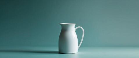 A white pitcher sitting on a table against a blue background photo