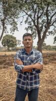 A man standing in front of a tree in a field photo