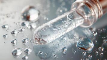 Close-up of clear liquid droplet in glass dropper on blue surface photo