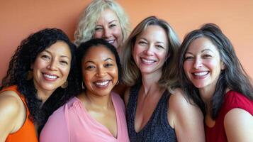 Diverse group of mature women smiling together against orange background photo