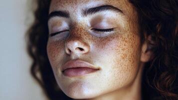 Peaceful asian female with freckles and curly hair with eyes closed in tranquil portrait photo