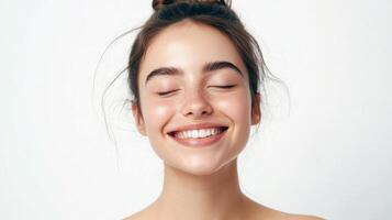Young caucasian female smiling with eyes closed against white background photo