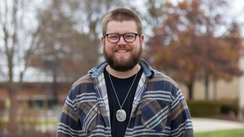 A man with glasses and a beard standing in front of a building photo