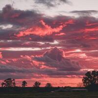 A red sky with clouds over a field photo