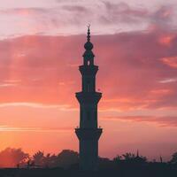 A mosque tower at sunset with clouds in the background photo