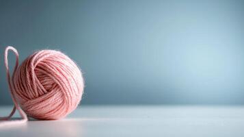light pink yarn ball rests softly on plain surface against blurred background photo