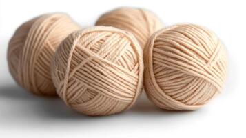 Four beige wool yarn balls with gentle shadows on white background photo
