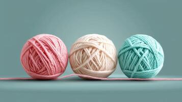 Three yarn balls in light pink, mint, and cream on soft green background photo