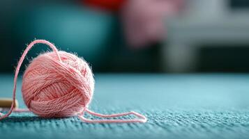 soft pink yarn ball rests on textured surface, creating cozy atmosphere photo
