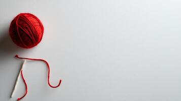 single red yarn ball with needle on white background, minimalistic style photo
