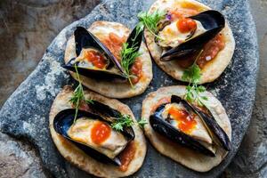 Crispy flatbreads topped with mussel pate and sauce enjoyed in a rustic setting photo