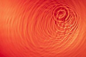 concentric waves of water droplets spreading over the surface of the water illuminated with red light photo