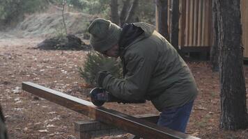 A person is sanding a wooden plank in a tranquil forest environment, surrounded by trees and autumn leaves. The early morning light creates a peaceful atmosphere for woodworking. video