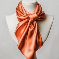 A vibrant orange satin scarf elegantly tied around a mannequin's neck, showcasing its luxurious texture and style. photo
