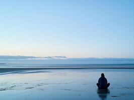 A serene scene of a person sitting alone on a beach at dusk, reflecting on the calm ocean and expansive sky. photo